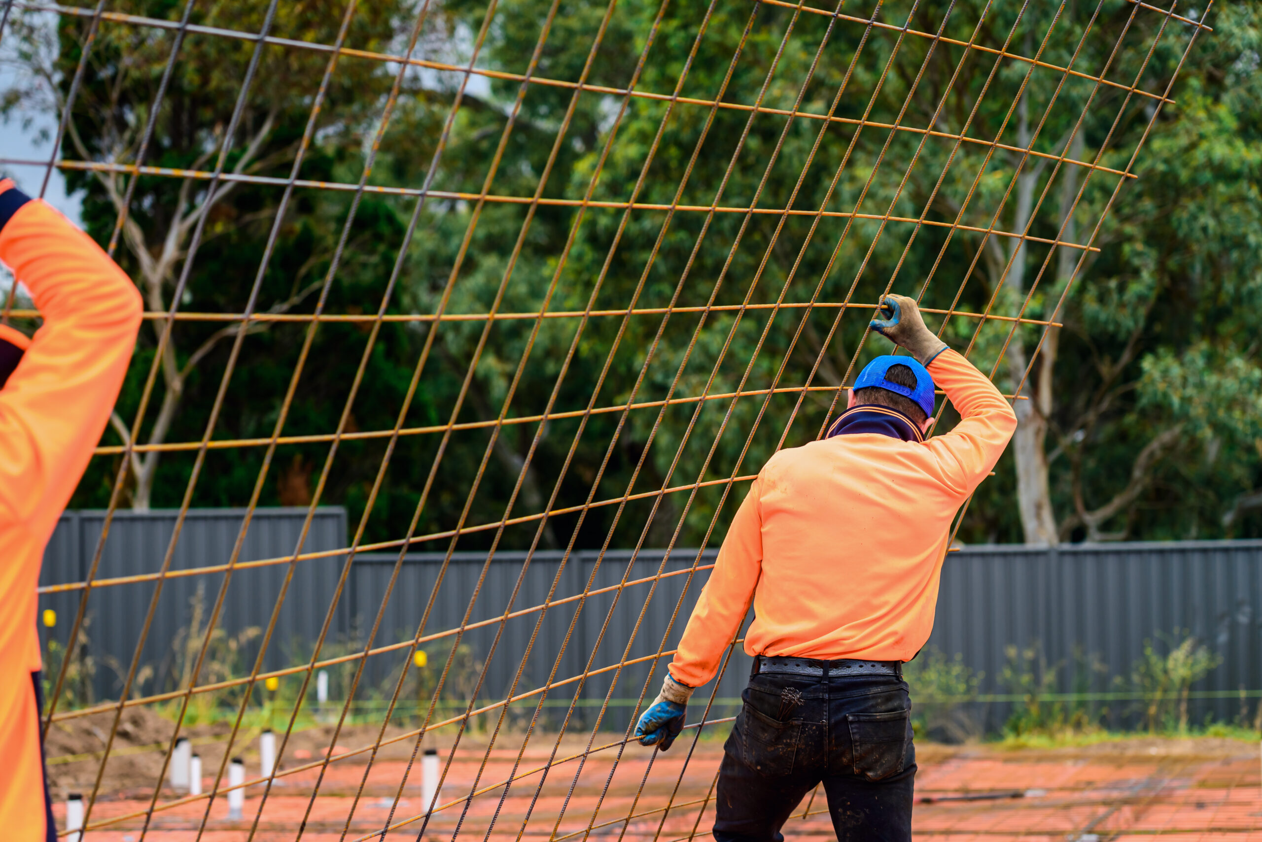 Australian builder carrying metal mesh required for new suburban house slab concreting