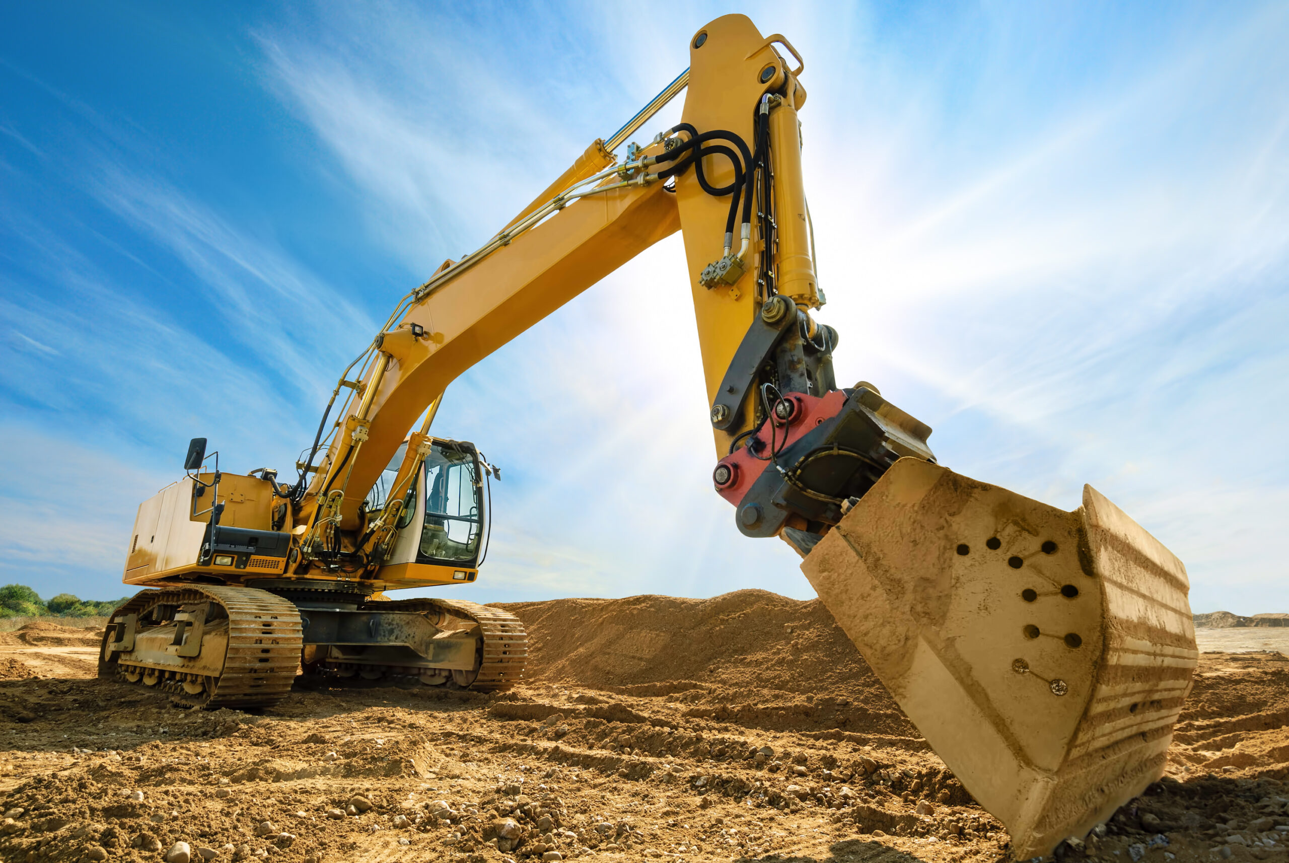 Großer Bagger mit Sonne und blauem Himmel im Hintergrund